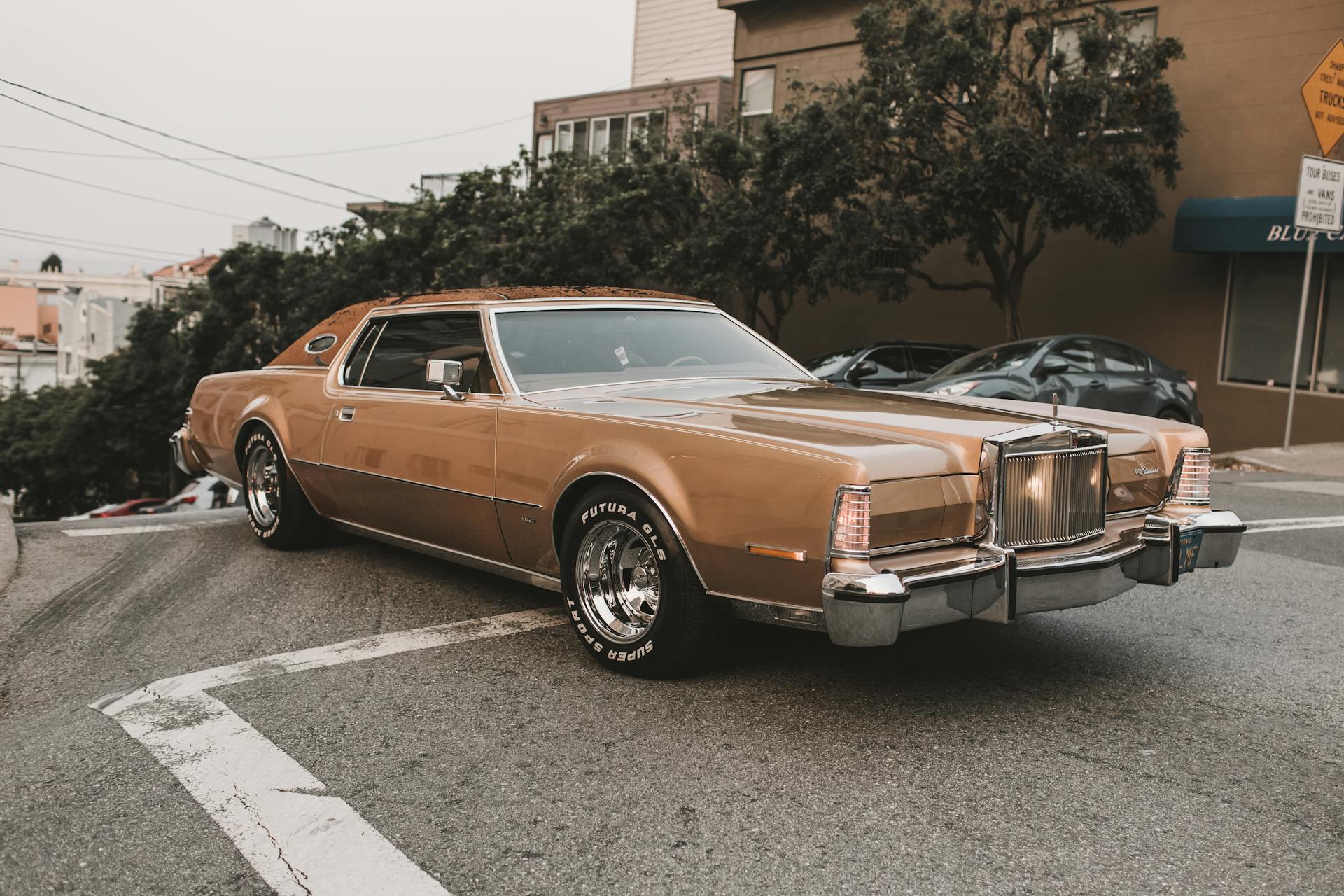 A classic vintage car parked on a sloped urban street in San Francisco.