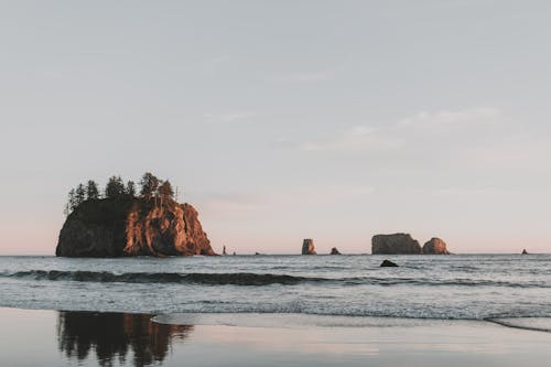 Brown Rock Formation on Sea Under White Sky