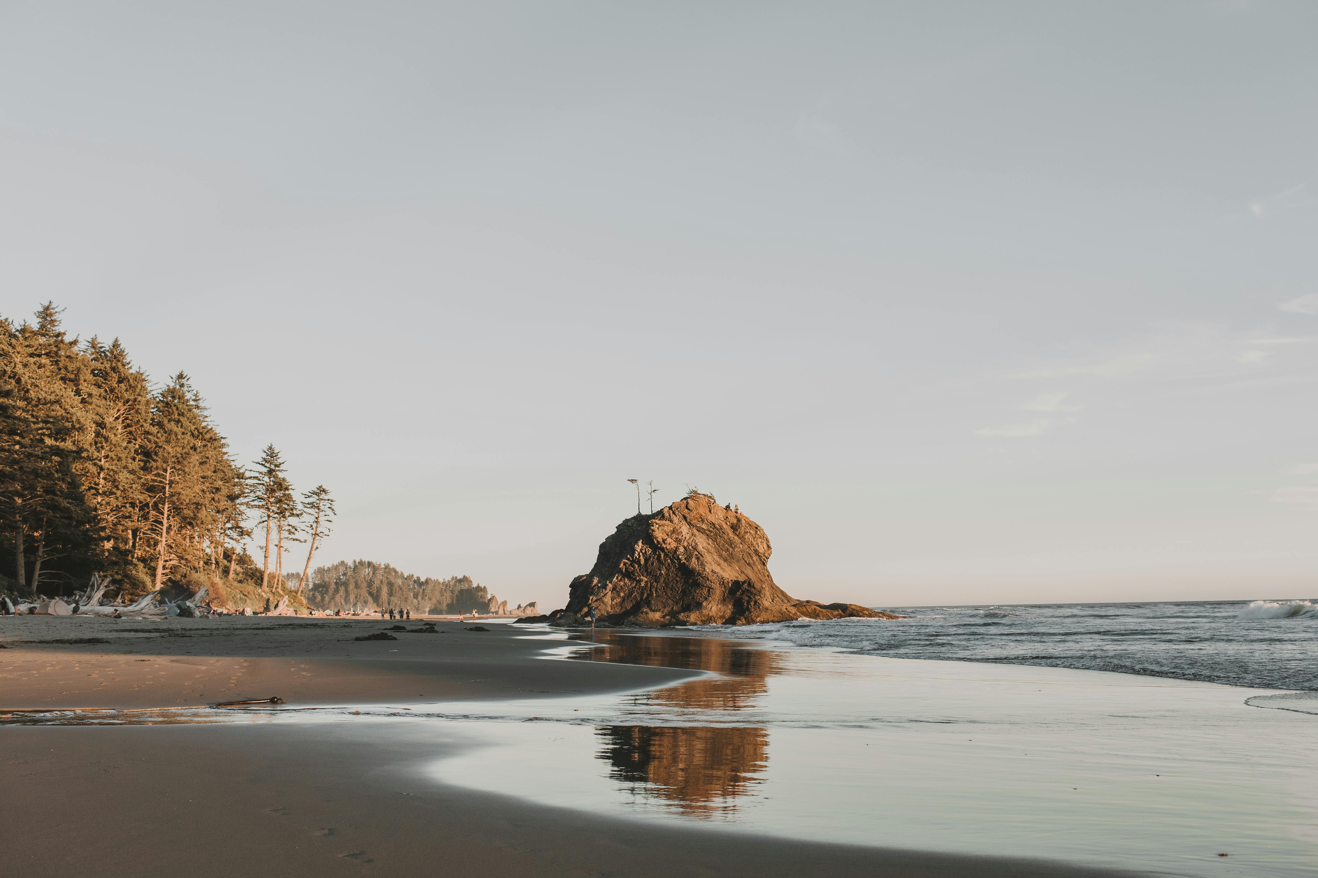 日落时分宁静的海滩景色，以天然岩石和海浪为特色，非常适合旅行爱好者