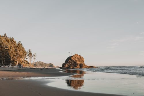 Free A tranquil beach scene at sunset featuring natural rock formations and waves, perfect for travel enthusiasts. Stock Photo