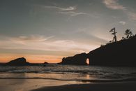 拱门岩石海滩上，日落与戏剧性的岩层和海浪交相辉映，令人叹为观止