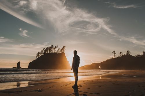 Free A lone figure stands silhouetted on a serene Washington beach at sunset, showcasing natural beauty and tranquility. Stock Photo