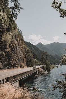 晴朗的天空下，美丽的山景中有一座桥，还有河流和道路