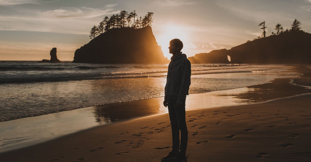 person standing alone on calm water at sunrise, contemplative mood