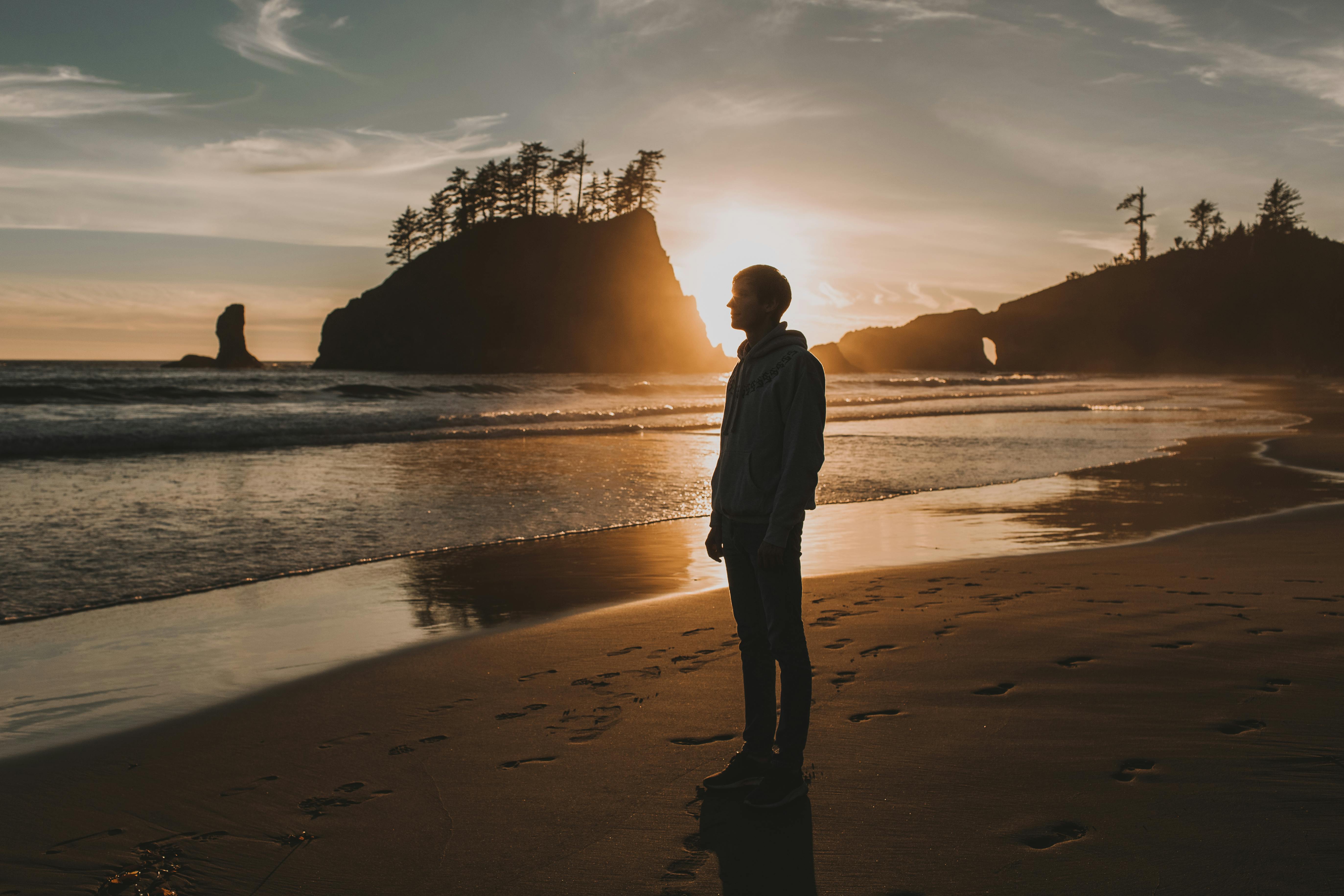 Silhouette Of Man Standing On Seashore During Sunset · Free Stock Photo