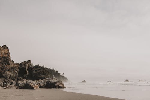 A Rock Formation Beside a Cluster of Rocks on the Shore