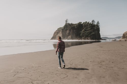 Photo of Man in Plaid Dress Shirt Walking on Beach