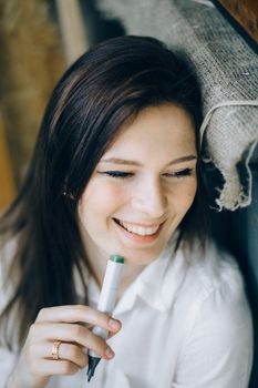 一个开朗的女人穿着白衬衫，拿着记号笔微笑，展现了她无忧无虑的态度