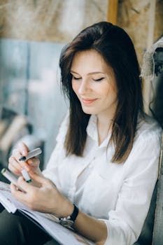 一位穿着白色休闲上衣的年轻女子微笑着，用记号笔在笔记本上写字