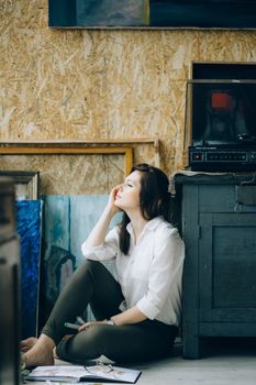 在创意工作室里，一位体贴的女人沉思地坐在木柜旁