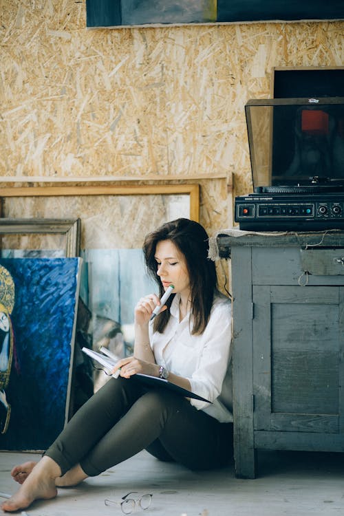 Woman in White Long Sleeve Shirt Sitting on Floor