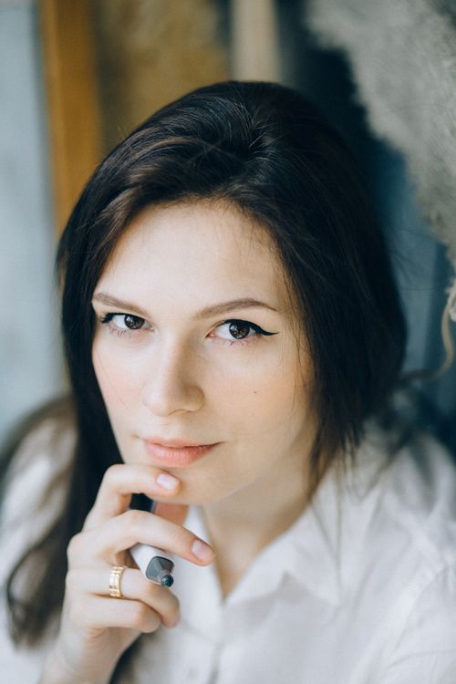 Free Elegant portrait of a woman in white shirt pondering indoors with natural light. Stock Photo
