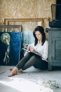 一个女人坐在艺术工作室里沉思，周围是绘画和灵感