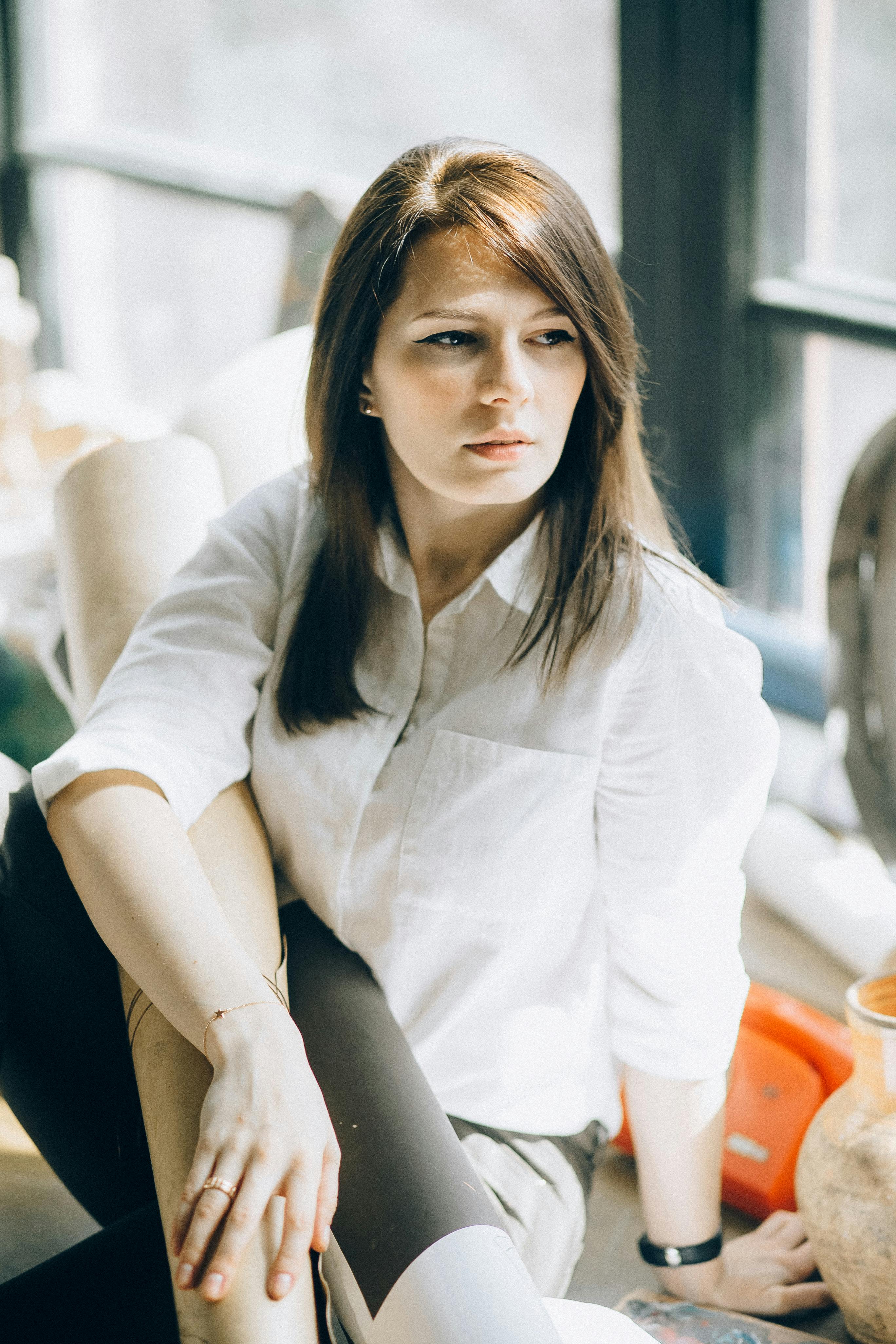 室内，一位穿着白衬衫的女人正沉思着