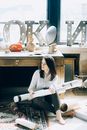 年轻女子坐在艺术工作室里，四周的创意材料和装饰散发着艺术魅力