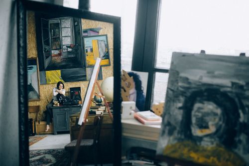 Free An art studio featuring paintings, a mirror reflection of a woman, and creative elements. Stock Photo