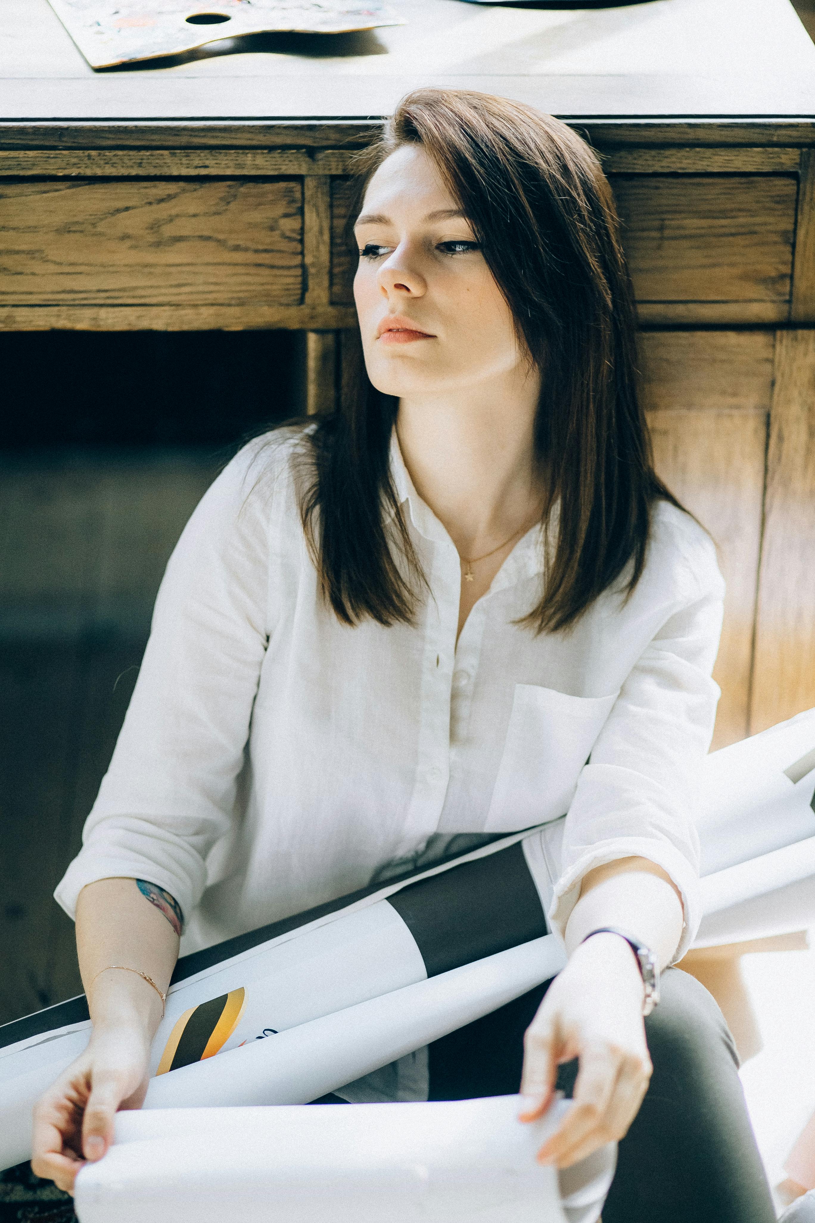 艺术工作室里，一位身穿白衬衫的年轻女艺术家体贴地坐着