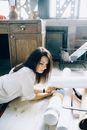 Woman in White Long Sleeve Shirt Sitting on Brown Wooden Floor