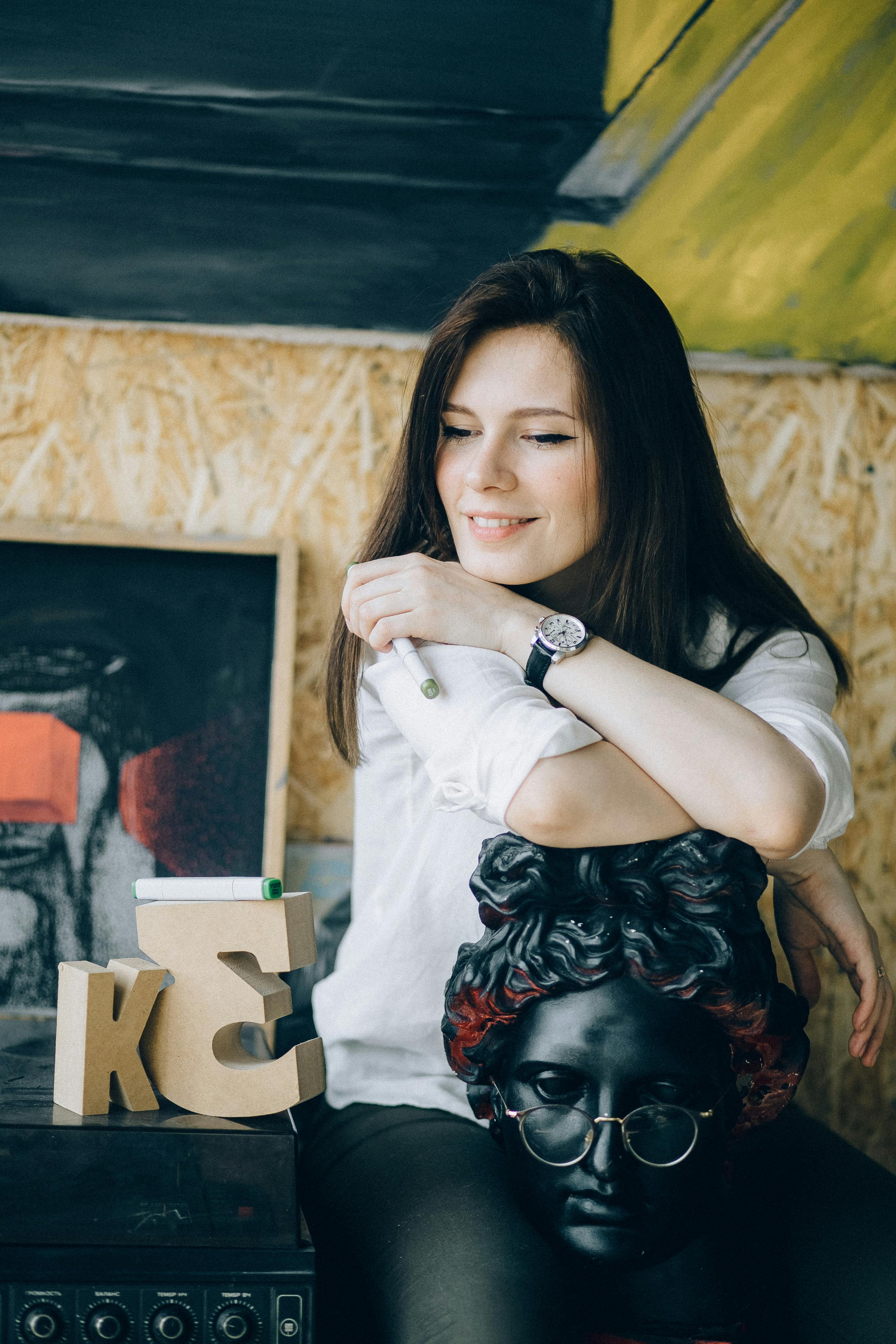 微笑的女人在白色上衣摆姿势创造性地与半身像室内