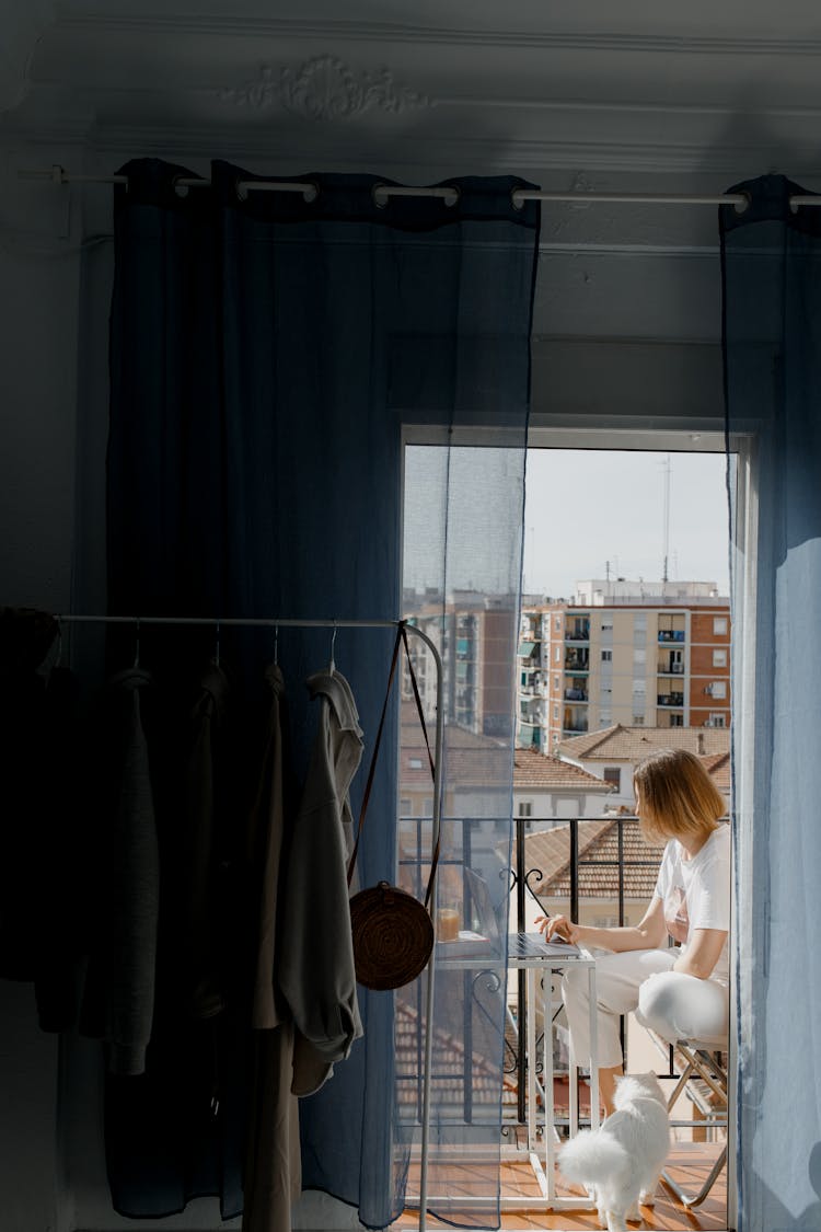 A Person Using A Laptop In The Balcony