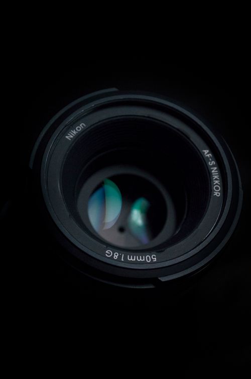 Free Detailed view of a camera lens showing reflections and aperture on black. Stock Photo