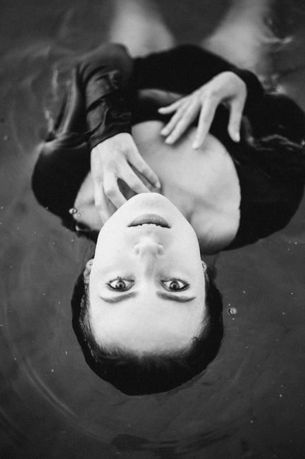 A captivating black and white portrait of a young woman floating in water, creating a serene and artistic effect.