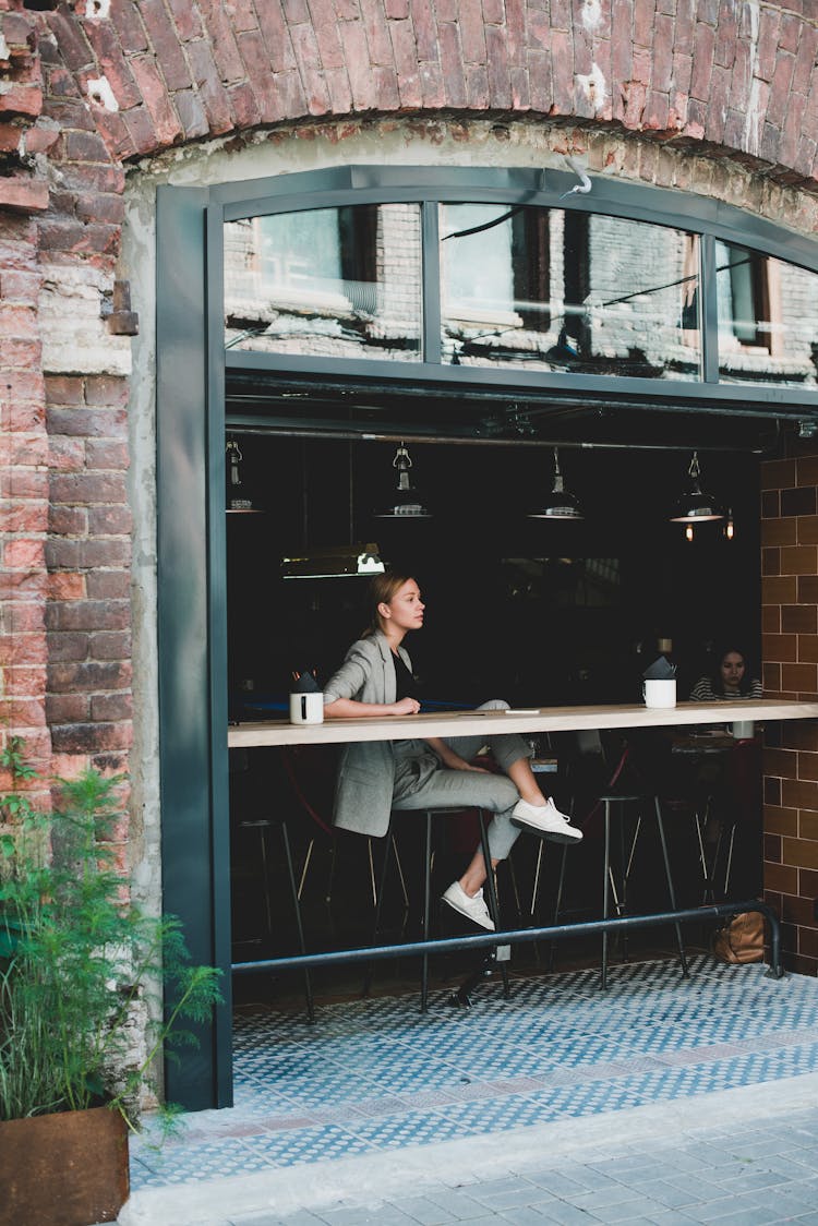 Stylish Calm Woman Sitting At Table In Cafe