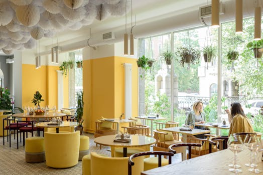 Bright café interior with lush plants and two women enjoying a casual conversation.