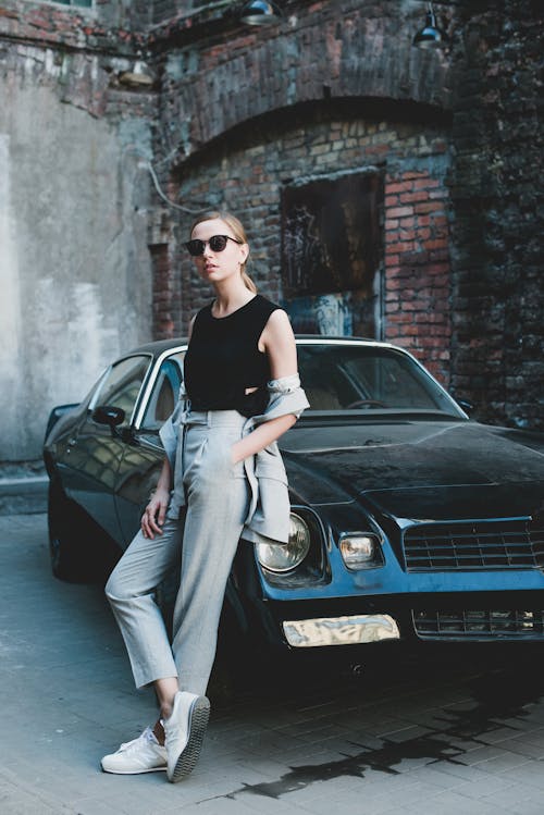 Stylish woman with hand in pocket leaning on retro car