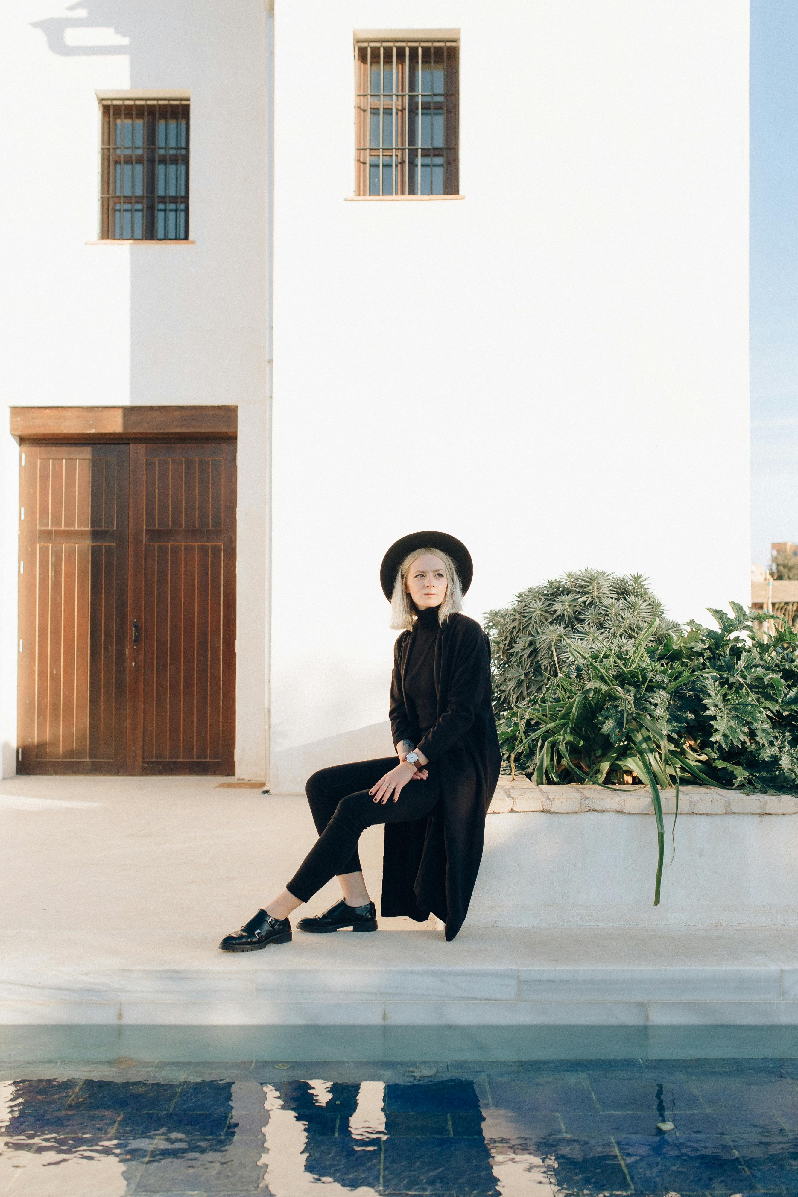 一位时尚女性身着黑衣，在现代建筑前摆姿势