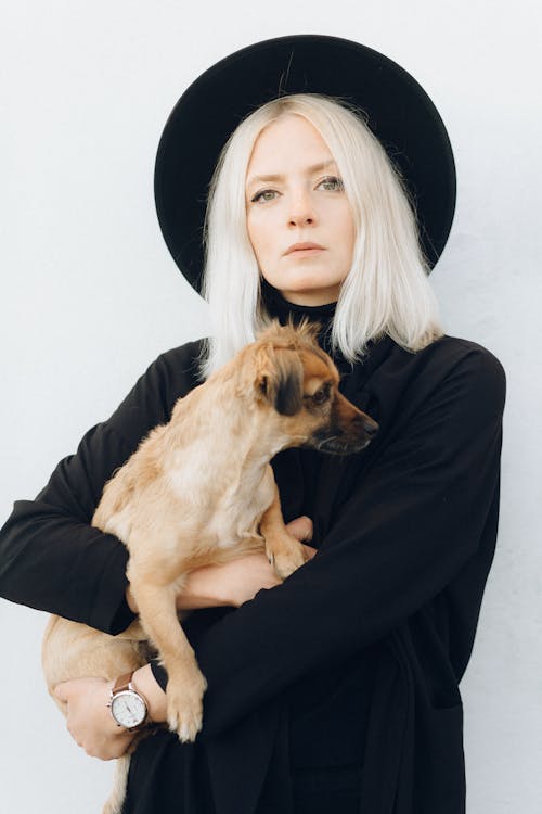 Woman in Black Long Sleeve Shirt Holding Brown Short Coated Dog