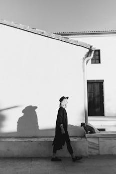 一幅优雅的黑白肖像中，一位戴帽子的女人正与狗并肩而行