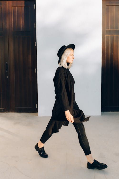 Woman in Black Coat and Black Hat While Walking