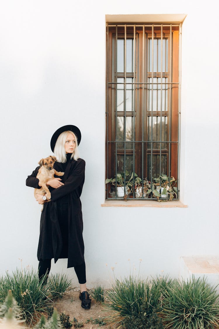 Woman In Black Clothes Carrying A Puppy