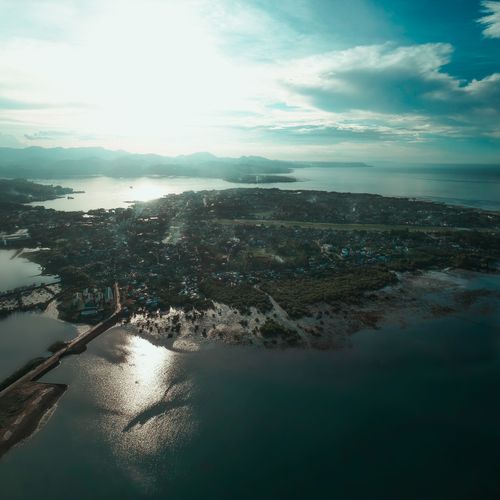 Free Drone view of settlement and woods on peninsula surrounded by large reservoir glistening in sunlight Stock Photo