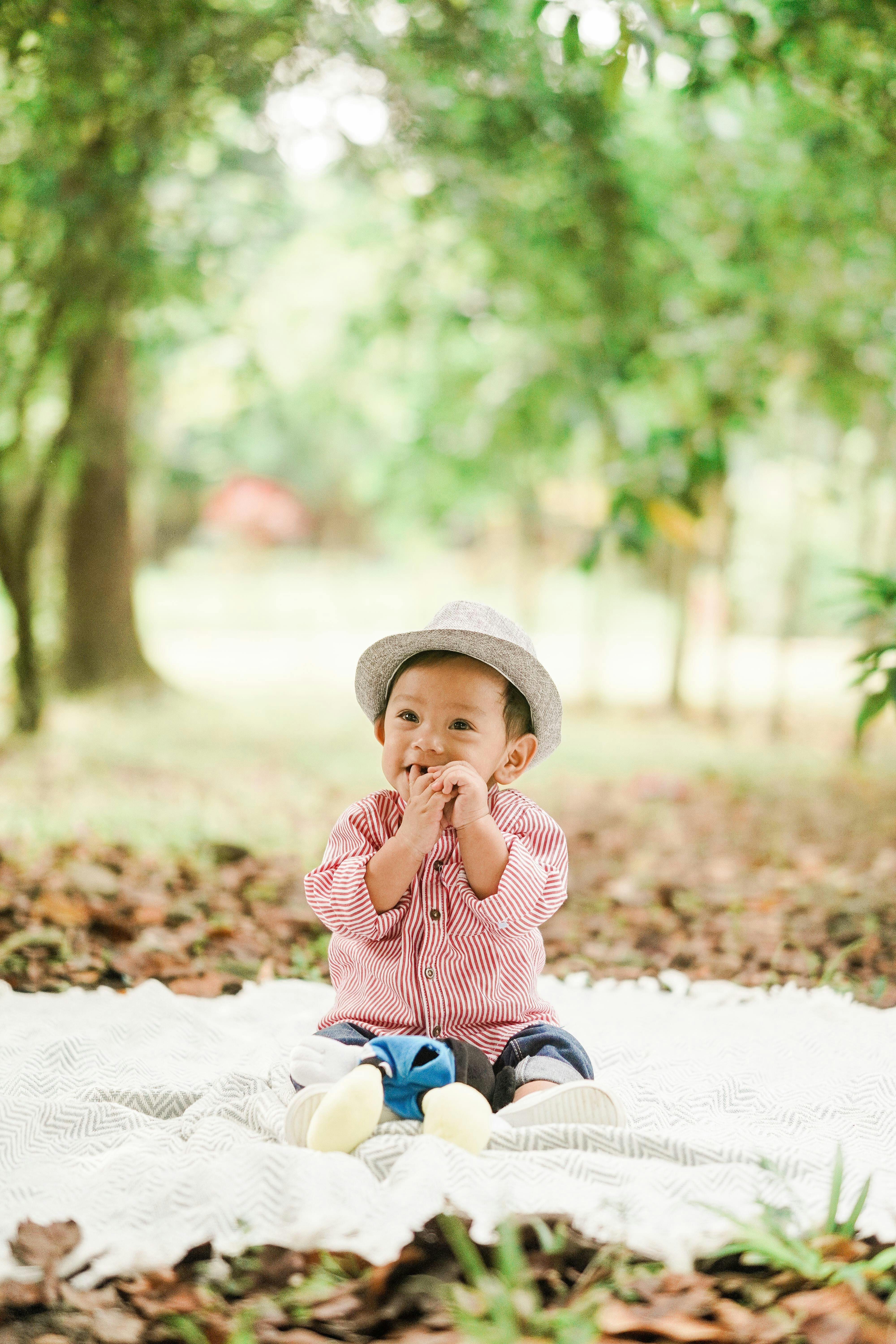 photo of child sitting on white blanket