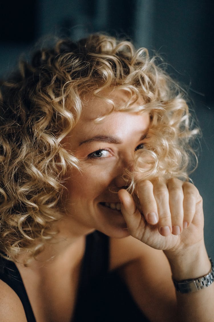 Blonde Haired Woman Smiling With Her Hand On Her Face