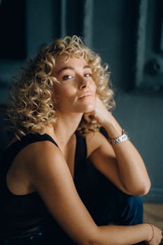 一位自信的女性肖像，卷曲的金发，身处室内，展现着风格与个性