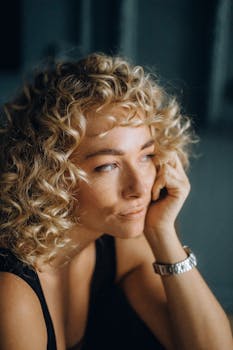 一位金发卷曲的体贴女人凝视着远方，唤起一种沉思的心情