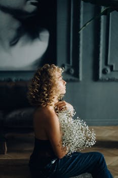 一位卷发女子在时尚的室内环境中拥抱着一束满天星