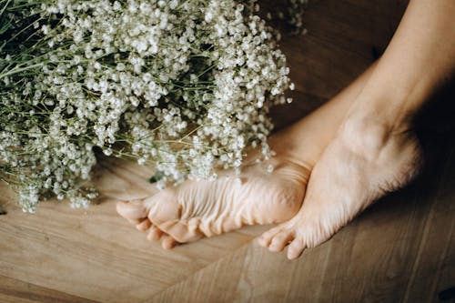 Free Person's Feet on Brown Wooden Floor Stock Photo