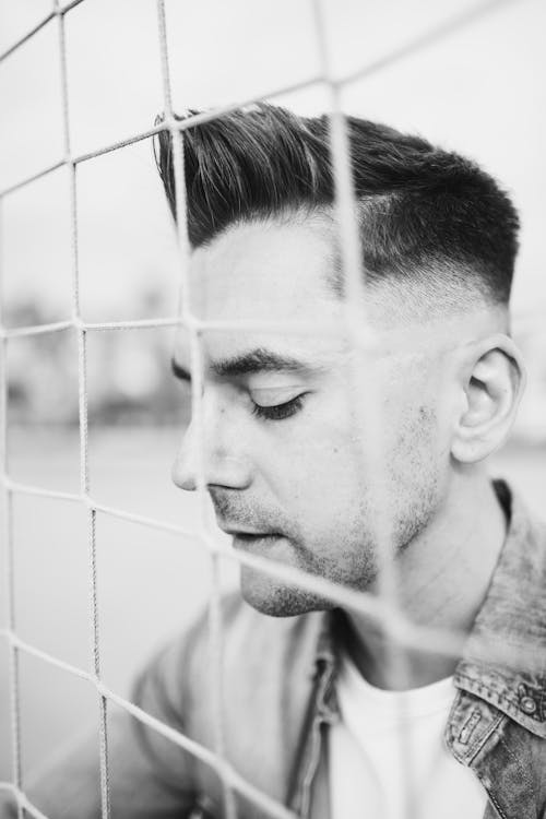 Black and White Photo of Man Behind Net