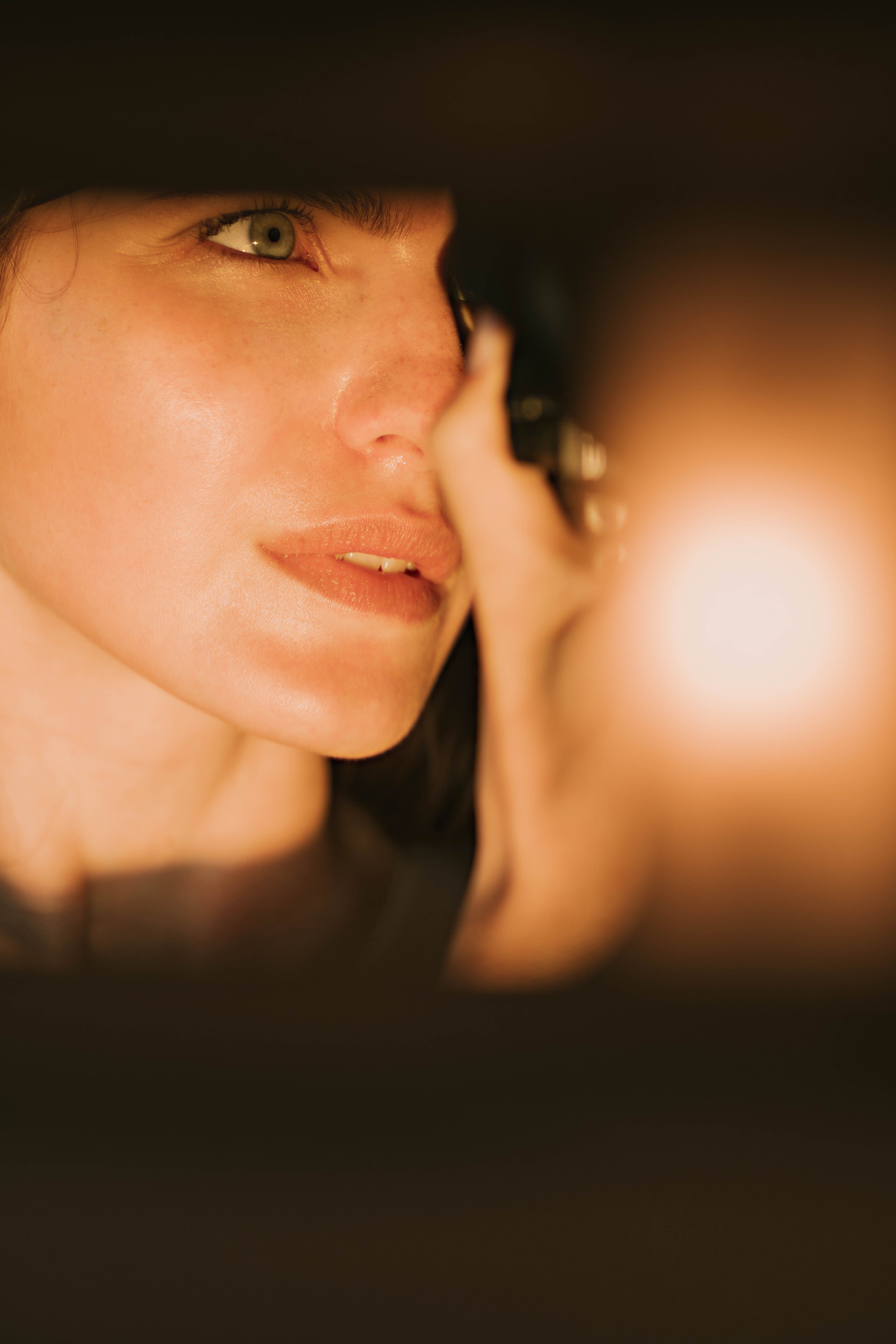 Artistic close-up portrait of a woman with warm atmospheric lighting and blurred background.