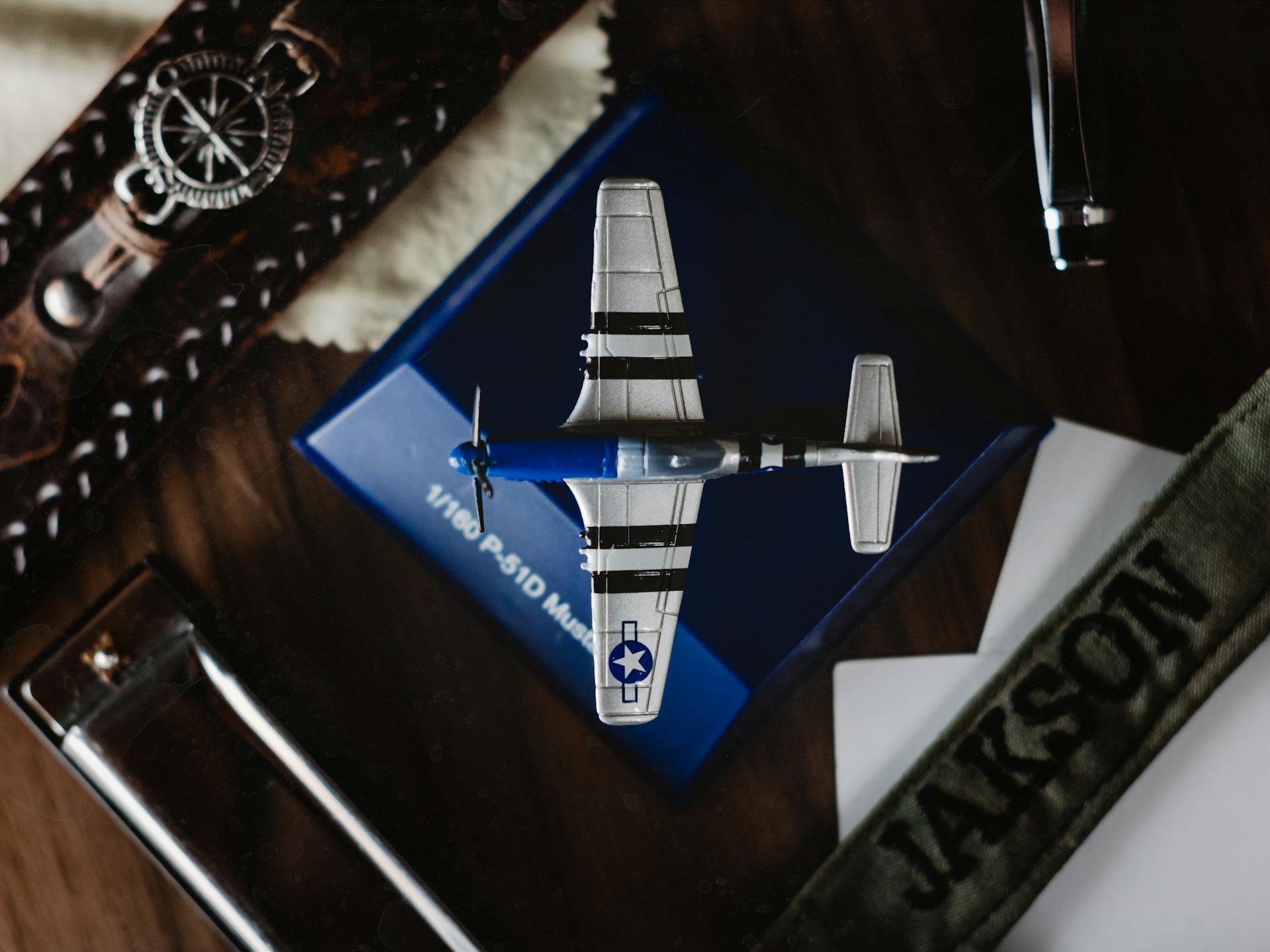 Overhead view of small blue figurine of aircraft on blue support surrounded by belts