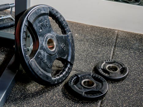 Black weight plates on a gym floor, ideal for strength training and workouts.