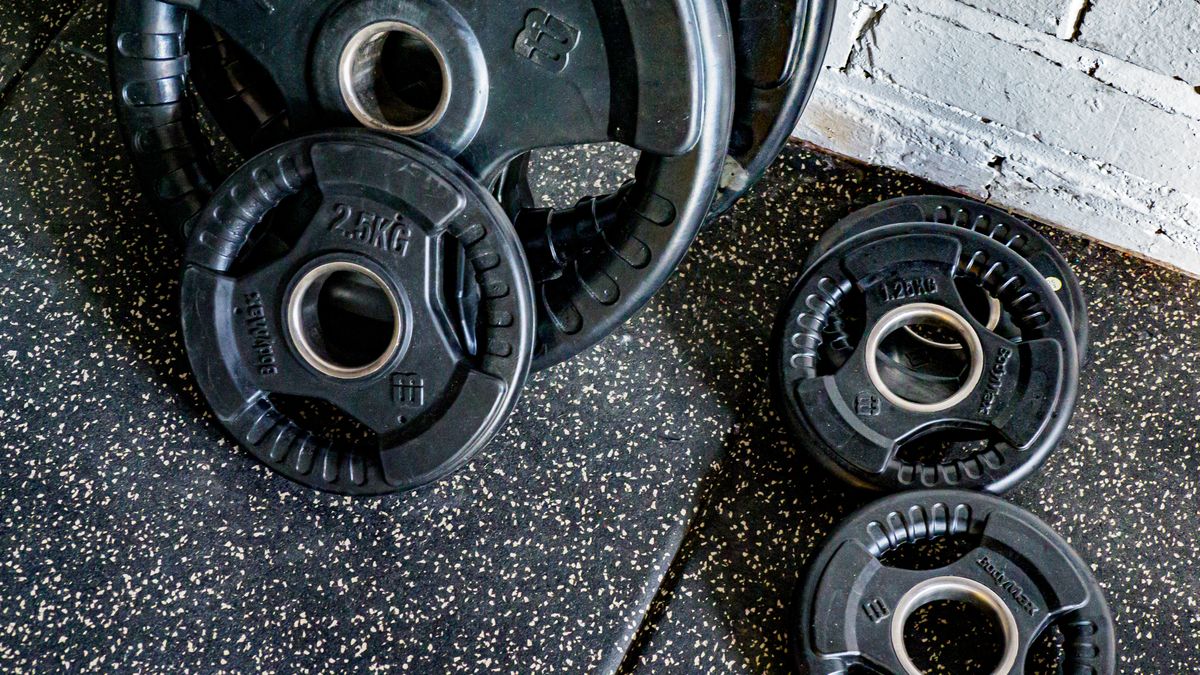 Close-up view of stacked weight plates in a gym environment against a textured wall.