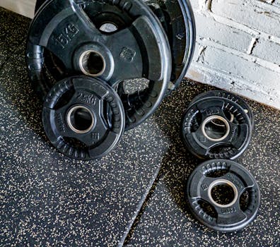 Close-up view of stacked weight plates in a gym environment against a textured wall.