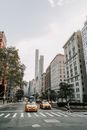 在纽约市高楼环绕的繁华街道上，一辆黄色出租车正在行驶