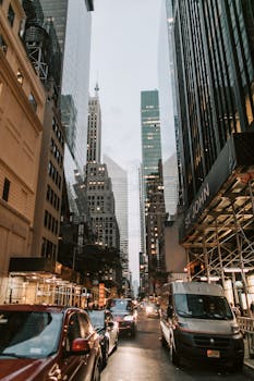 Vibrant street view of New York City's downtown bustling with cars amidst towering skyscrapers.
