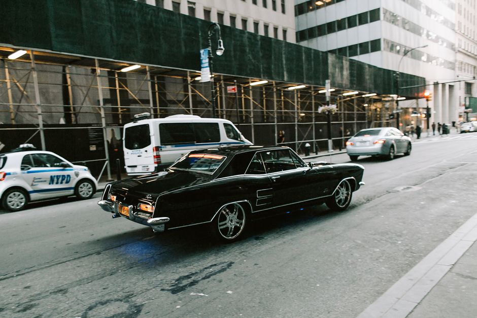 A retro black classic car captured on a bustling New York City street, evoking nostalgic charm.